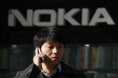 A man using his mobile phone walks under a Nokia logo in Shanghai