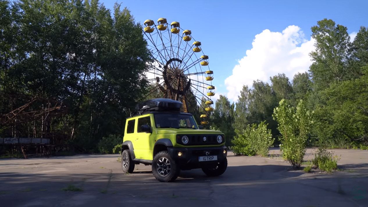 Suzuki Jimny з номерним знаком IGTRIP на тлі занедбаного колеса огляду в парку розваг Прип'яті