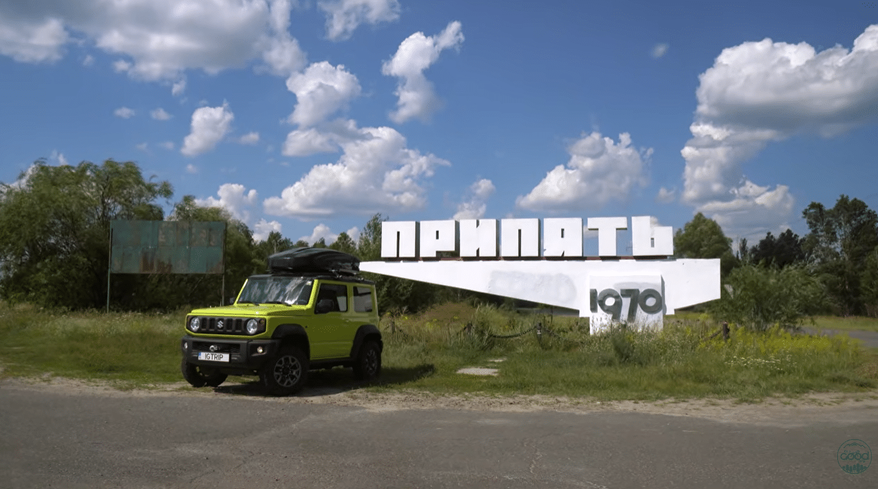Жовтий позашляховик Suzuki Jimny біля стели «Прип'ять 1970» на в'їзді до покинутого міста