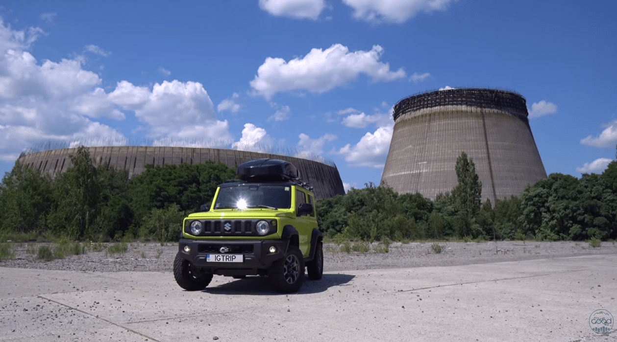 Жовтий позашляховик Suzuki Jimny з написом IGTRIP на тлі недобудованої градирні ЧАЕС