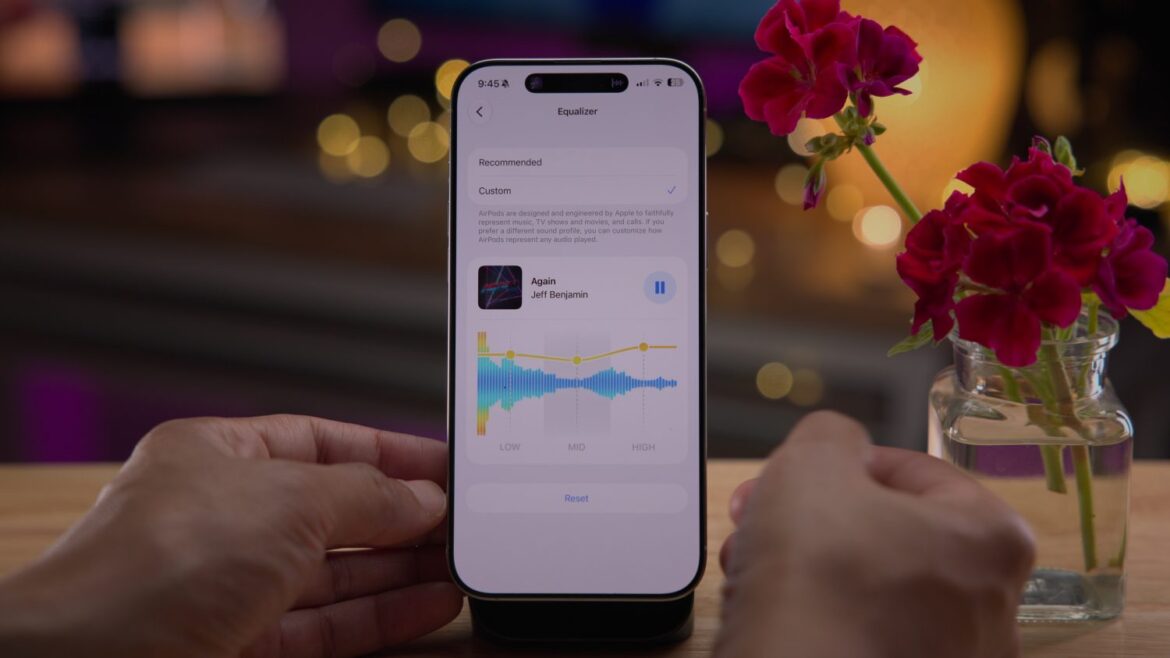 IPhone зі світлим інтерфейсом налаштувань AirPods та еквалайзером, рядом стоїть ваза з червоними квітами
