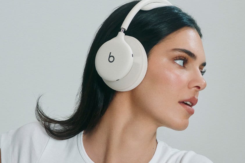 Жінка у профіль носить білі навушники Beats 360 на голові