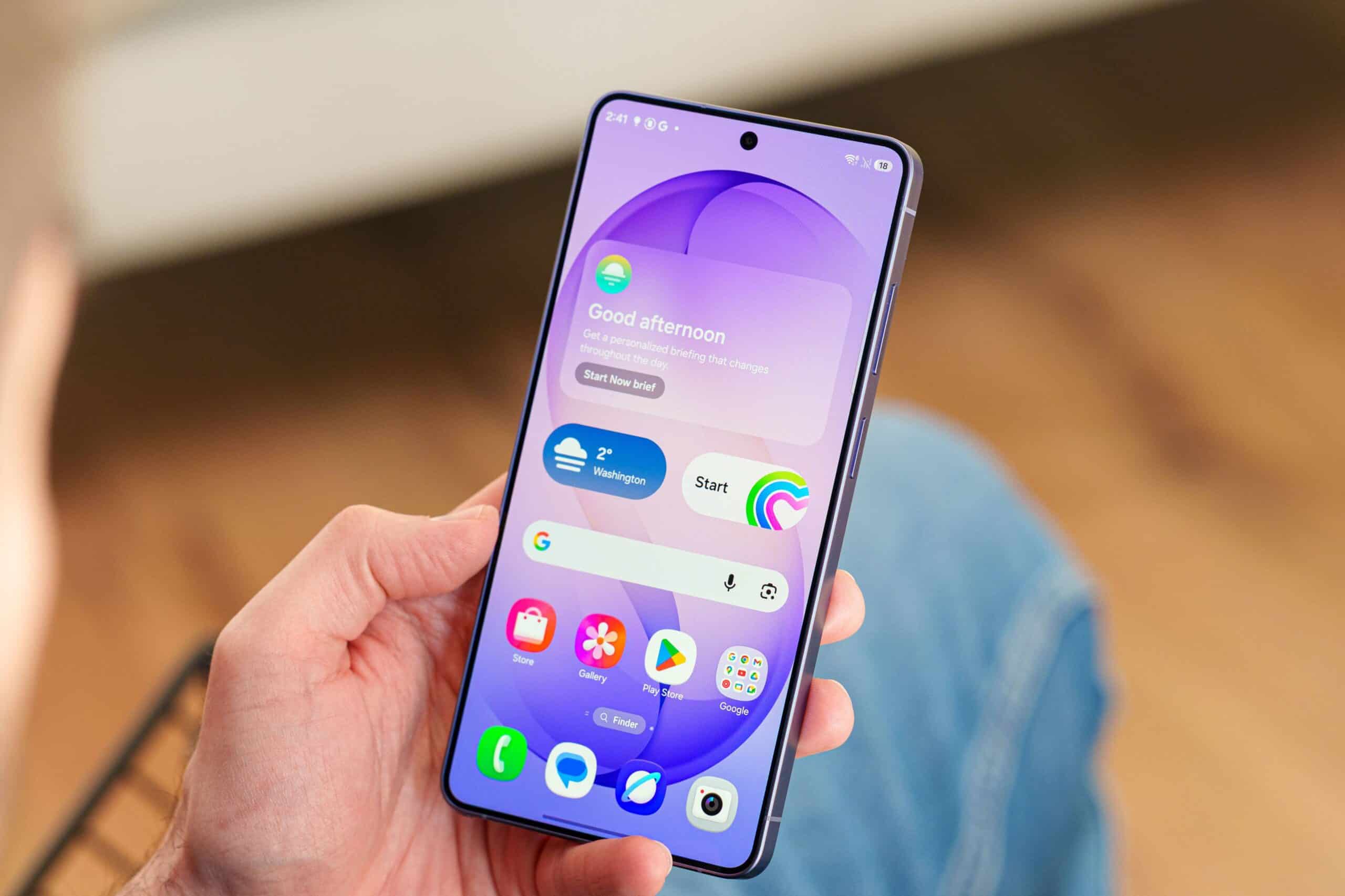 Смартфон Samsung Galaxy S27 у руці з фіолетовим градієнтом екрана та повідомленням про добрий день
