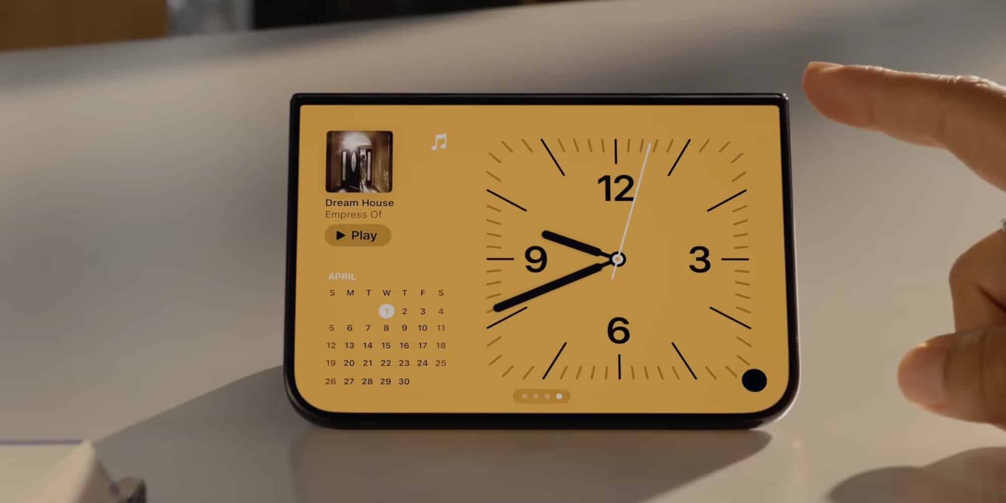 Режим StandBy на iPhone Duo з циферблатом аналогових годинників на жовтому фоні та календарем на квітень