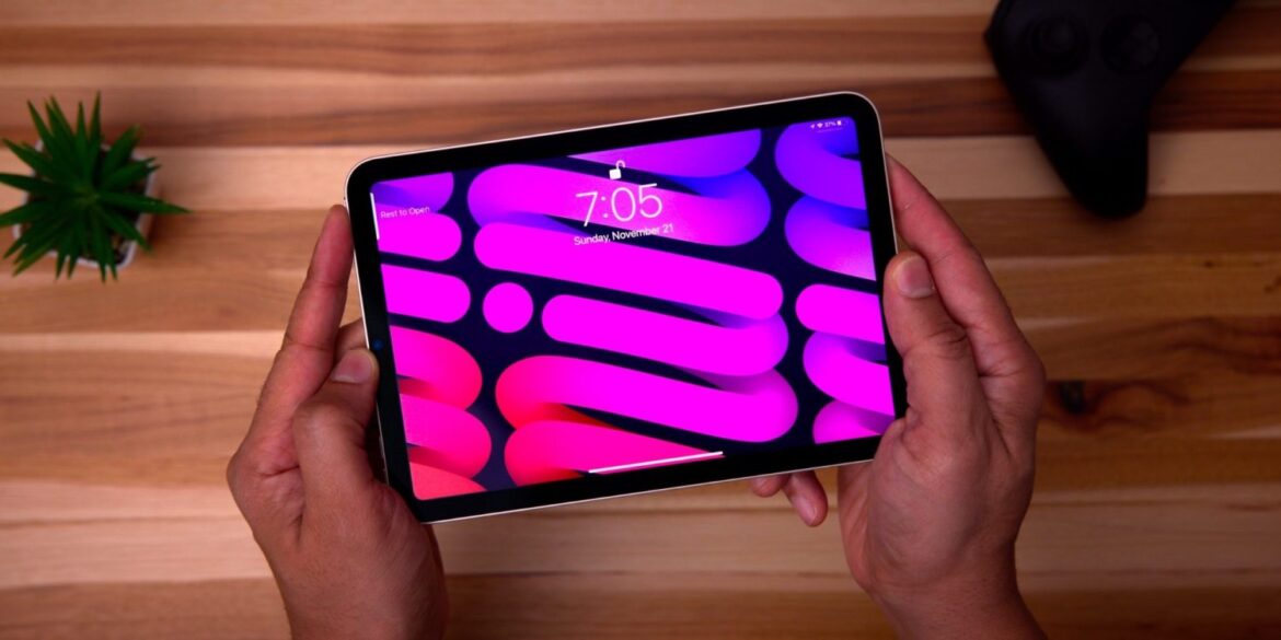 Людина тримає планшет iPad mini з яскравим рожево-фіолетовим дисплеєм, що демонструє нову OLED-панель пристрою