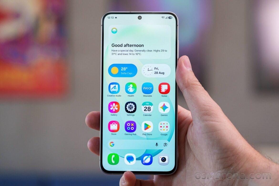 Смартфон Samsung з домашнім екраном, що показує погоду 28 градусів та різноманітні додатки, в руці користувача