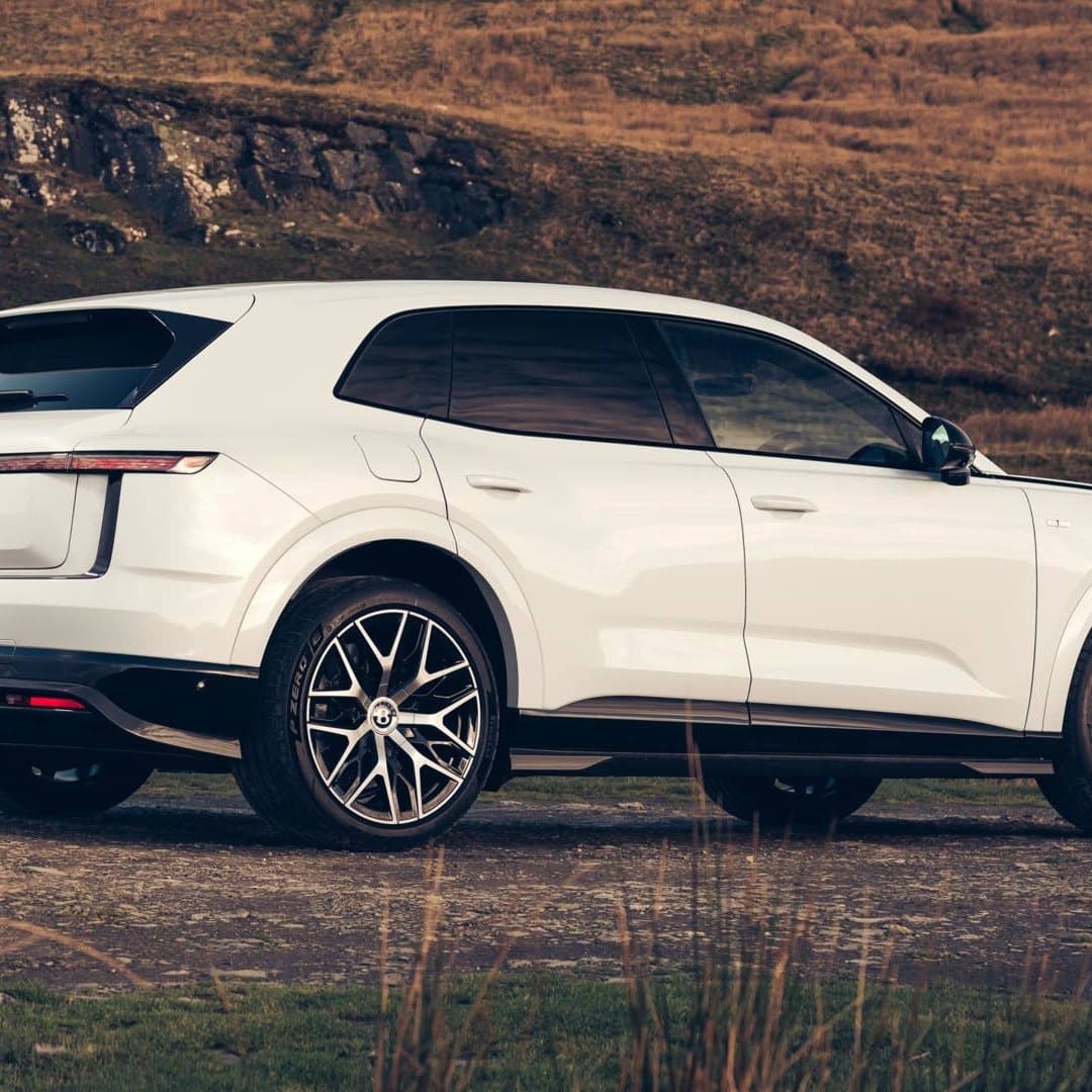 Білий Bentley Torcal ззаду під три чверті на фоні схилу та озера з видним логотипом на кришці багажника