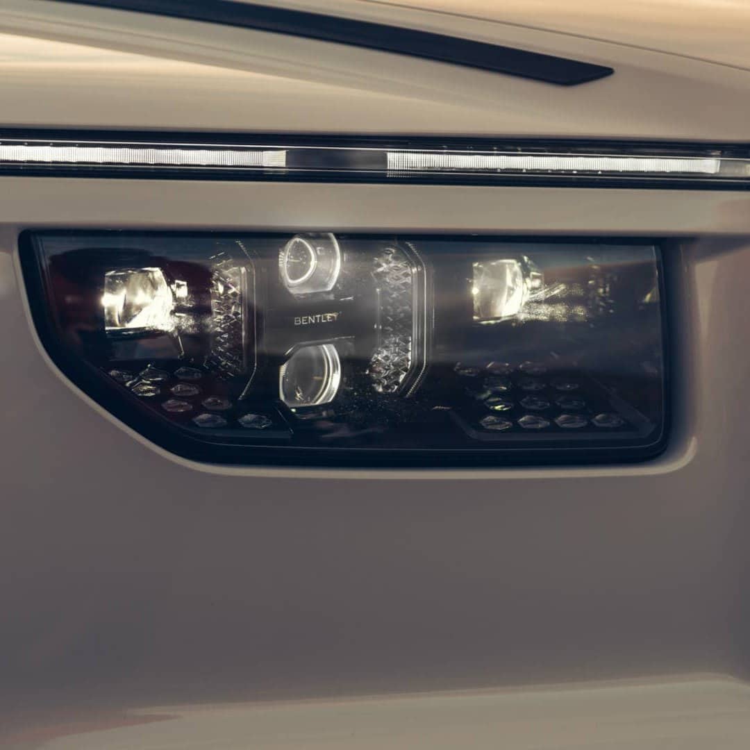 Крупний план LED-фари білого автомобіля з вузькою смугою денних ходових вогнів і решіткою з ромбовим плетінням