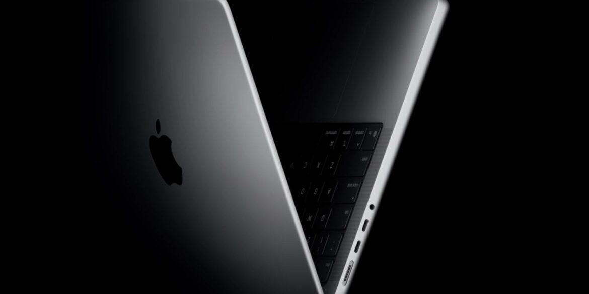 Два розкритих MacBook Pro з металевим корпусом на чорному фоні, один із видимою клавіатурою