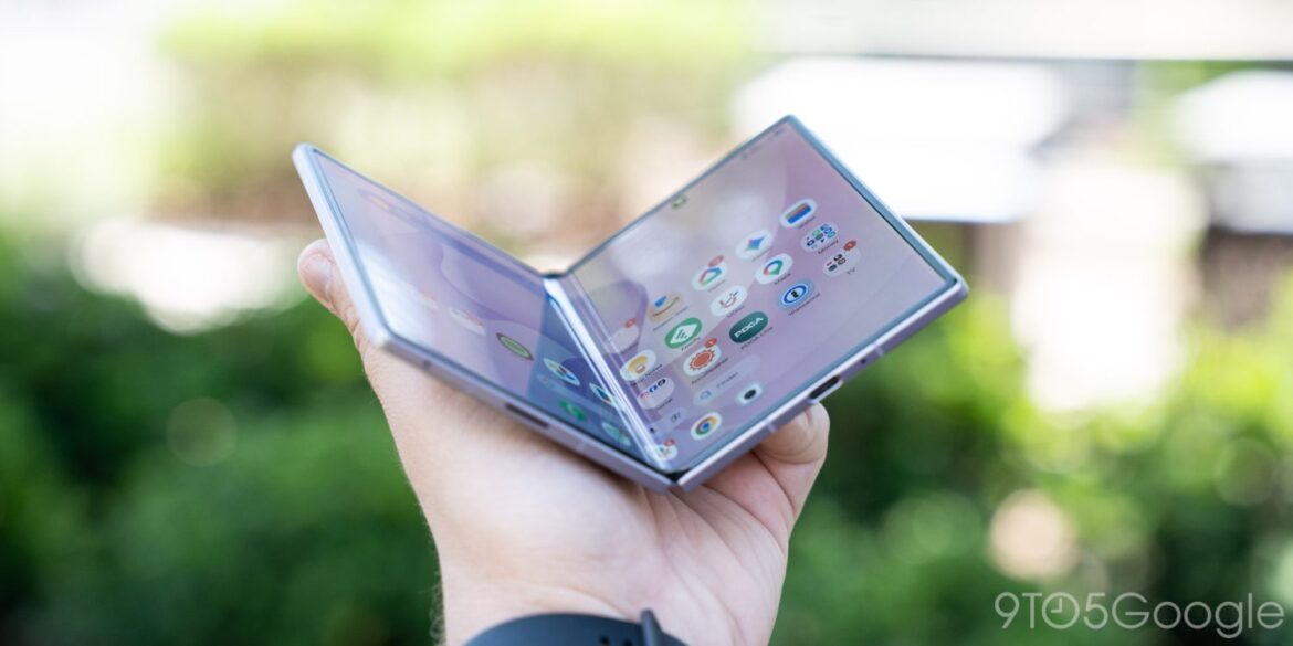 Складаний смартфон Samsung Galaxy Z Fold 8 у розкритому вигляді в руці на фоні розмитого зеленого оточення