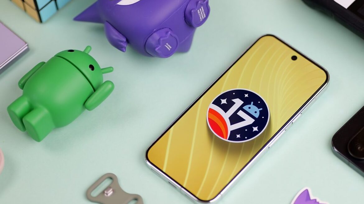 Смартфон із логотипом Android 17 на жовтому екрані серед фігурок андроїда та іграшок на м'ятному столі