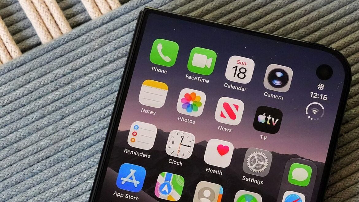 Екран iPhone з іконками Phone, FaceTime, Photos, Settings та App Store на сіро-блакитній тканині