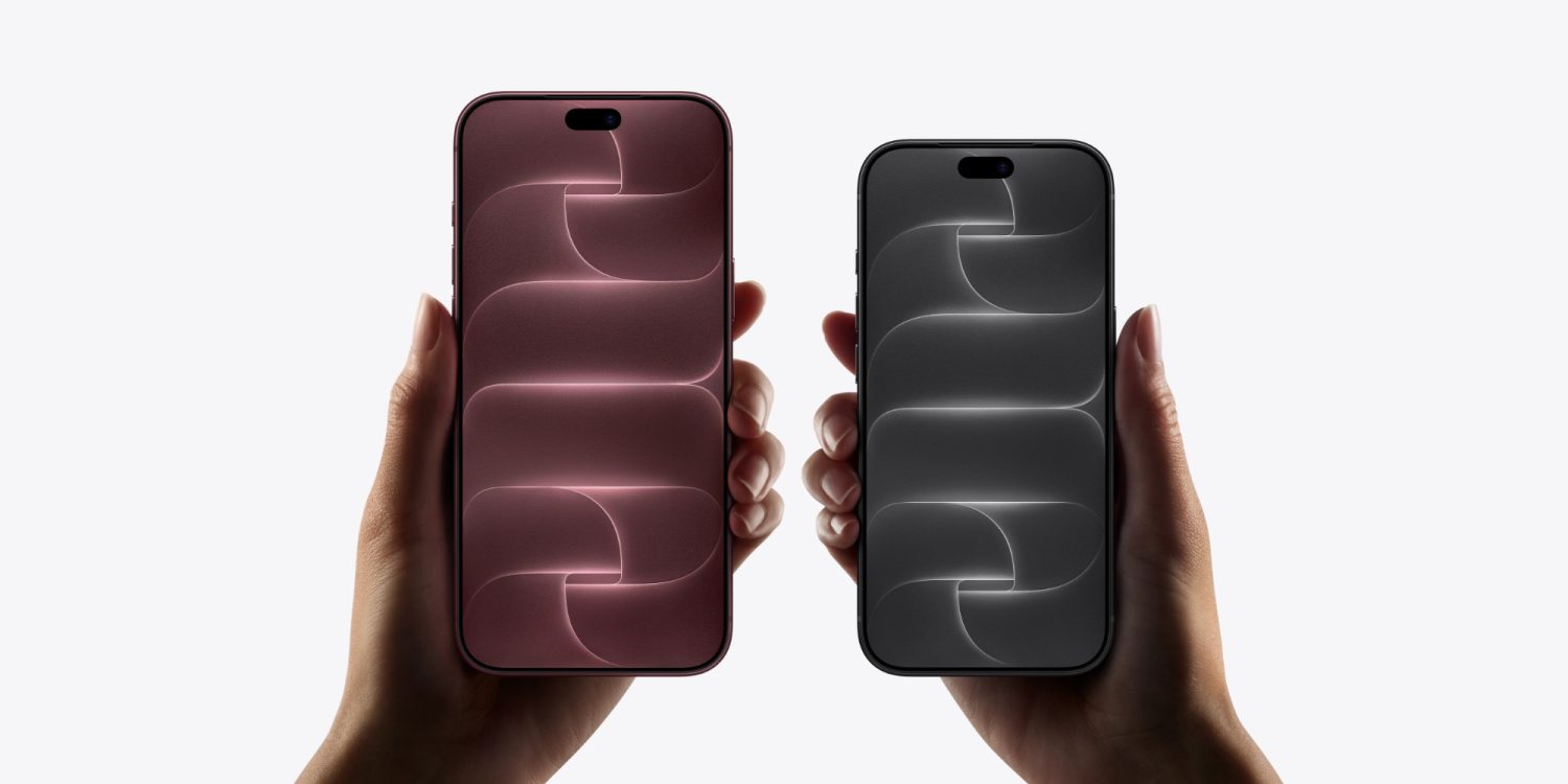 Дві руки тримають смартфони iPhone з бордовим та чорним екранами, що показують геометричний дизайн заставки