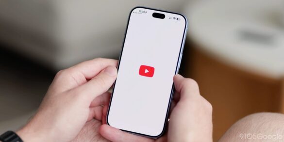Смартфон у руках користувача з червоним логотипом YouTube на білому екрані