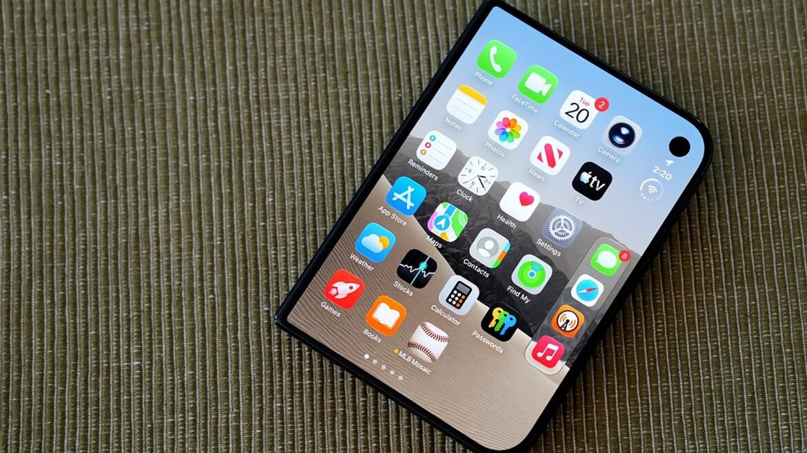 Складний смартфон з головним екраном iOS і закругленим краєм лежить на текстурованій оливково-зеленій поверхні