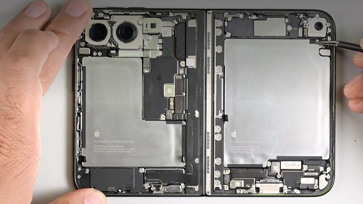 Розібраний складаний смартфон: дві батареї з логотипом Apple, камери та плата, поруч руки з інструментом