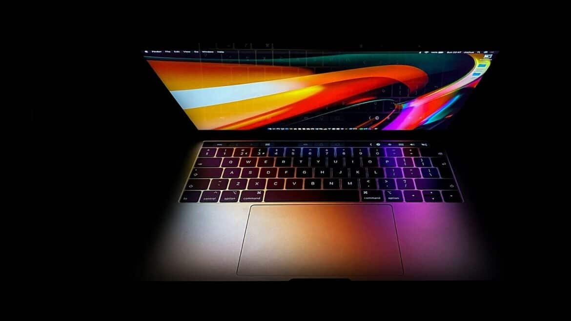 Відкритий MacBook Pro у темряві: екран з помаранчево-червоними хвилями та підсвічена клавіатура