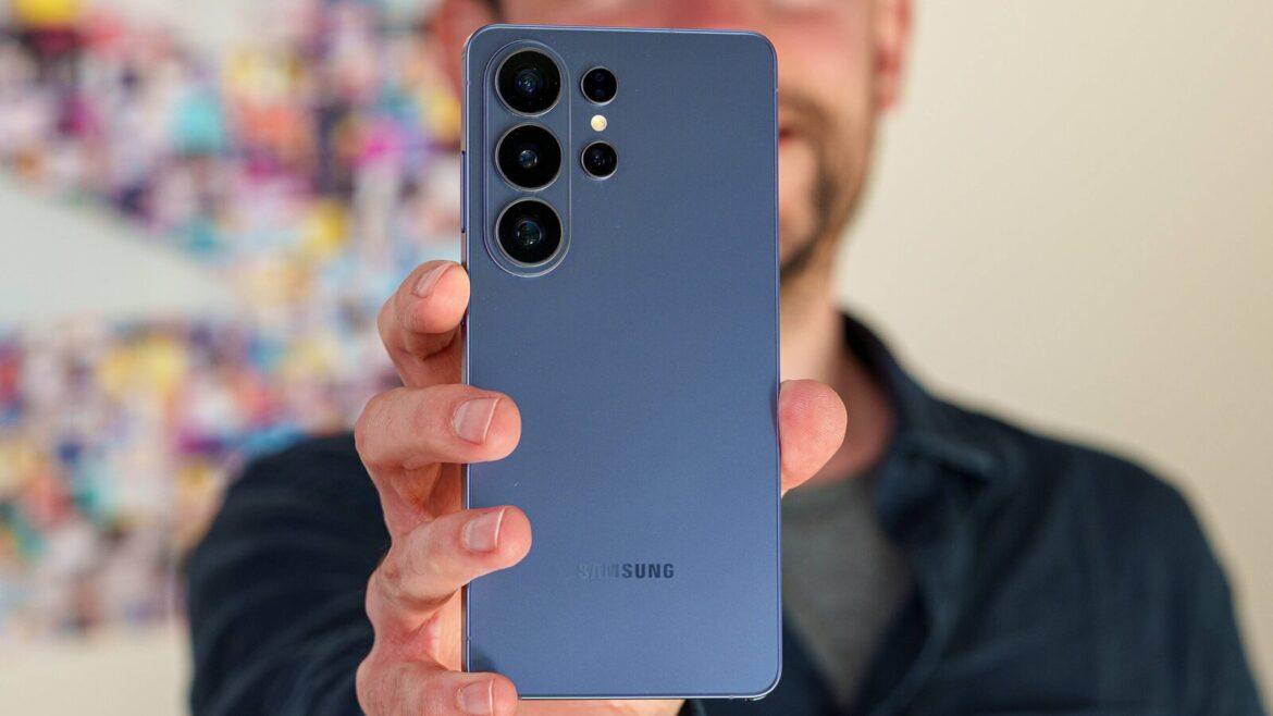 Чоловік тримає темно-синій смартфон Samsung задньою панеллю до камери, видно блок із кількох камер і напис SAMSUNG
