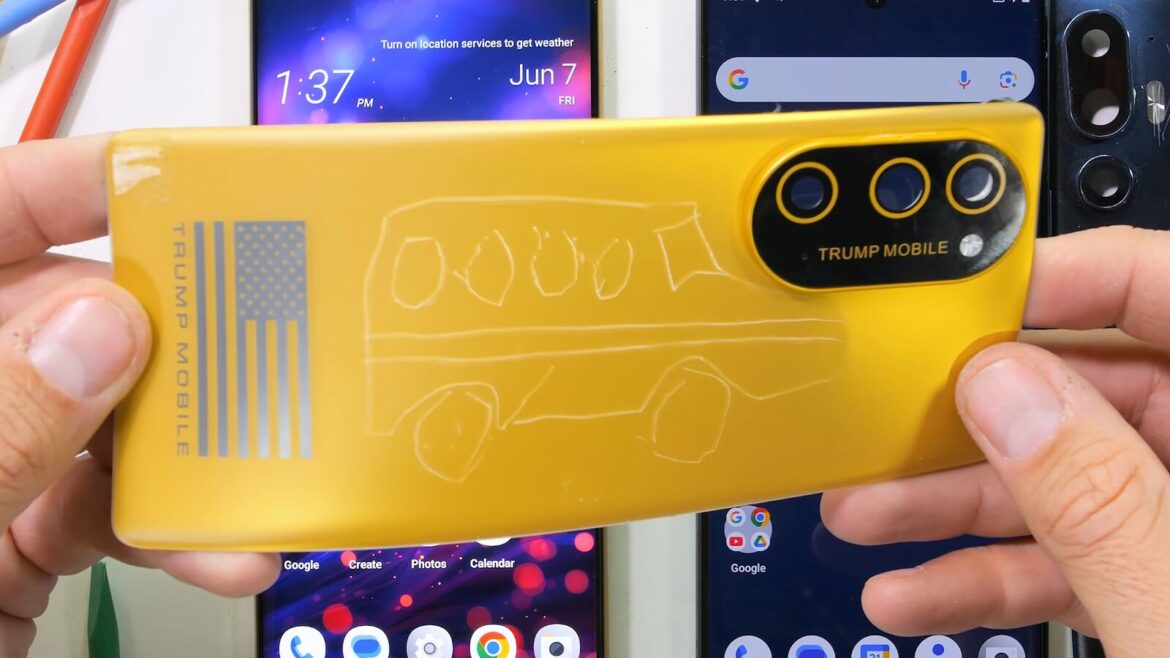Руки тримають жовтий телефон Trump Mobile з намальованим автобусом на кришці і прапором США